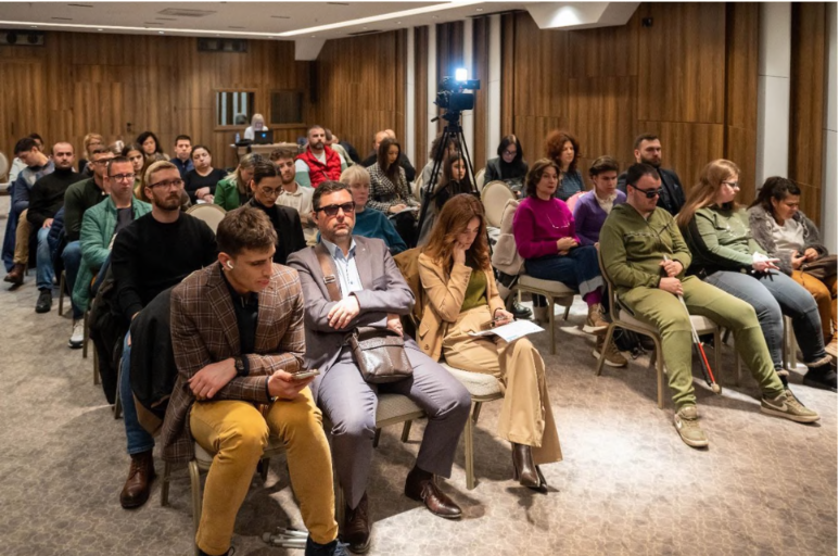 Audience sitting and listening attentively in a conference hall.