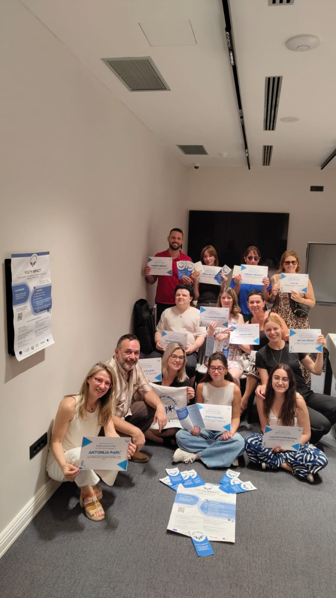 Training participants are posing in a meeting room, holding certificates from a completed trainer training within the Youth IMPACT project.